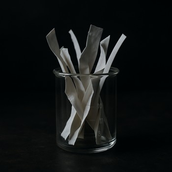 Crumpled scent strips gathered in a glass beaker