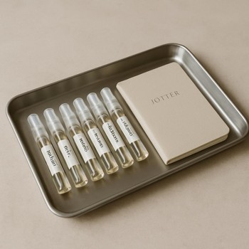 Metal tray carrying small perfume bottles and a jotter