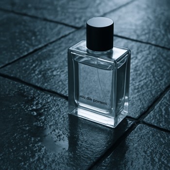 Perfume bottle next to wet stone tiles after rain