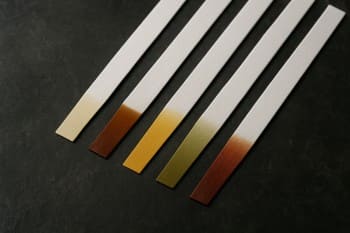 White scent strips dipped into different perfume accords on a dark table